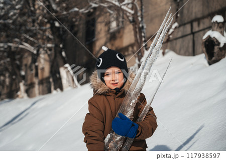 A Caucasian boy holds an icicle in his hands outside in winter A Caucasian boy holds an icicle in his hands outside in winter 117938597