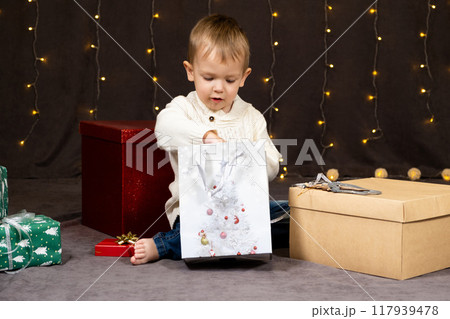 Little two-year-old boy opens Christmas gifts at home 117939478