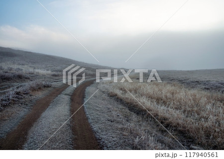 Morning dirt road through the foggy mountain plateau. 117940561