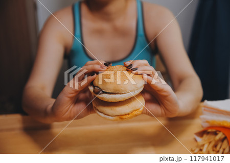 Binge eating disorder concept with woman eating fast food burger, fired chicken , donuts and desserts Binge eating disorder concept with woman eating fast food burger, fired chicken , donuts and desserts 117941017