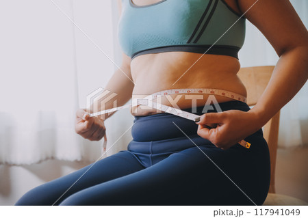 fat woman, fat belly, chubby, obese woman hand holding excessive belly fat with measure tape, woman diet lifestyle concept fat woman, fat belly, chubby, obese woman hand holding excessive belly fat with measure tape, woman diet lifestyle concept 117941049