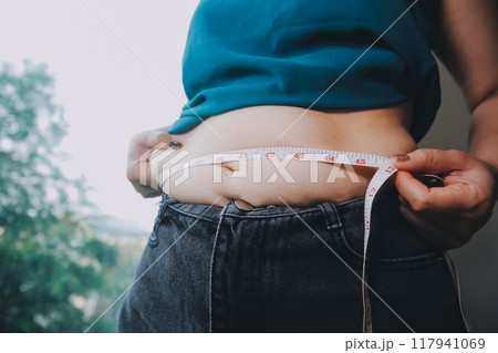 fat woman, fat belly, chubby, obese woman hand holding excessive belly fat with measure tape, woman diet lifestyle concept fat woman, fat belly, chubby, obese woman hand holding excessive belly fat with measure tape, woman diet lifestyle concept 117941069