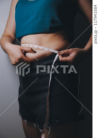fat woman, fat belly, chubby, obese woman hand holding excessive belly fat with measure tape, woman diet lifestyle concept fat woman, fat belly, chubby, obese woman hand holding excessive belly fat with measure tape, woman diet lifestyle concept 117941084