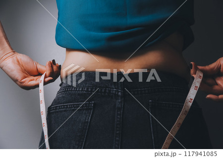 fat woman, fat belly, chubby, obese woman hand holding excessive belly fat with measure tape, woman diet lifestyle concept 117941085