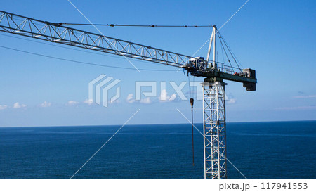 Lifting construction crane on the background of the sea. Construction of facilities by the sea. Industrial crane for cargo transportation 117941553