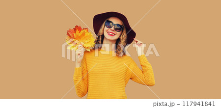 Autumn portrait of happy smiling young woman holding yellow leaves, stylish cheerful girl in sweater Autumn portrait of happy smiling young woman holding yellow leaves, stylish cheerful girl in sweater 117941841