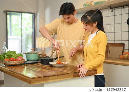 Loving young couple preparing meal together at wooden countertop 117942237