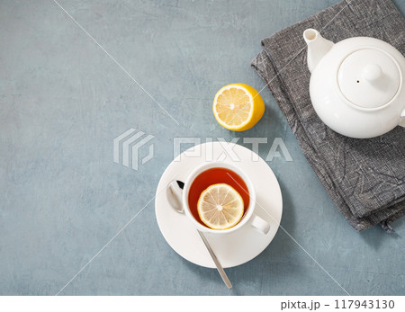 A cup of herbal tea with lemon and teapot on a blue  background.  117943130