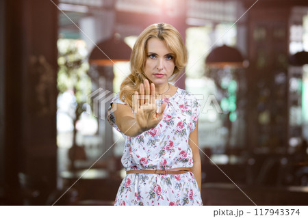 Portrait of sad negative woman show her palm as sign of prohibition. Restaurant interior in the background. Portrait of sad negative woman show her palm as sign of prohibition. Restaurant interior in the background. 117943374