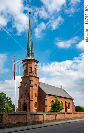 Faxe Ladeplads, Seeland, Denmark, July 23, 2024 -  Brick stone church of the village aginst blue sky 117944676