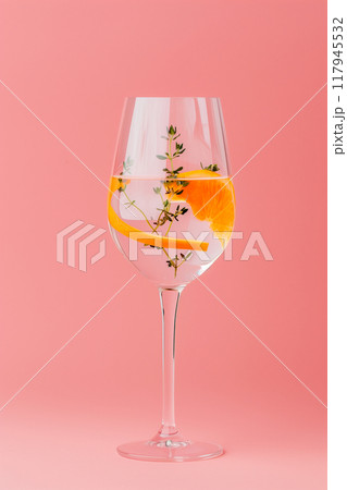 A glass of water with a slice of orange and a sprig of thyme 117945532