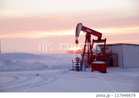 One red pump jack in the agricultural field covered with snow in winter in the sunset time. One red pump jack in the agricultural field covered with snow in winter in the sunset time. 117946679