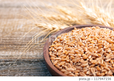 Wheat in a plate on a wooden table and dry yellow ears. Wheat in a plate on a wooden table and dry yellow ears. 117947156