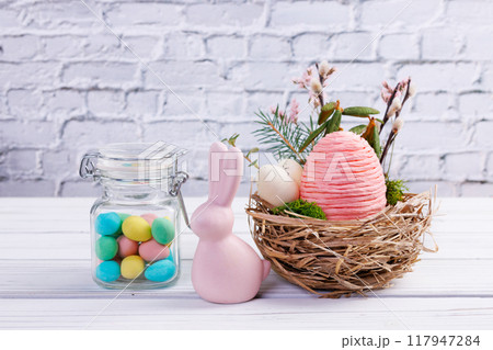 Easter nest with eggs and branches, bunny and jar with candies. 117947284