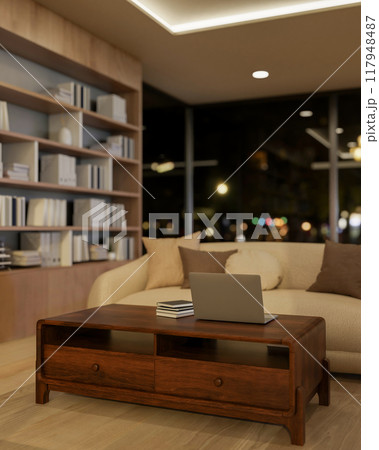 A laptop on a beautiful vintage wooden coffee table in a contemporary living room at night. 117948487