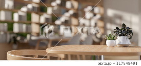 A product display space on a minimalist wooden table in a cozy, contemporary coffee shop or library. 117948491