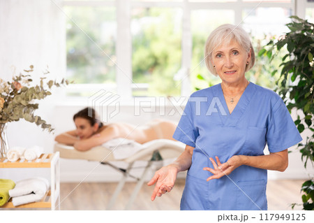 Elderly woman masseuse posing in spa salon Elderly woman masseuse posing in spa salon 117949125
