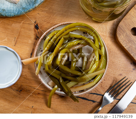 Pickled wild garlic scapes served in ceramic bowl 117949139