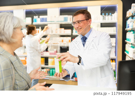 Elderly woman client consults with pharmacist which medicinal ointment to buy 117949195