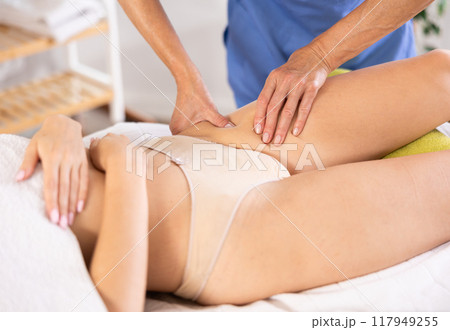Masseuse doing thigh massage to young woman 117949255