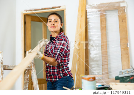 Woman carrying wooden planks in new apartment 117949311