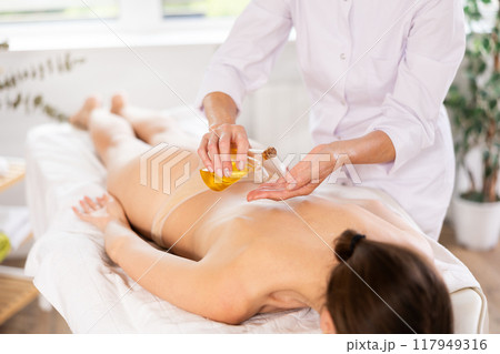 Masseuse giving oil massage to young woman Masseuse giving oil massage to young woman 117949316