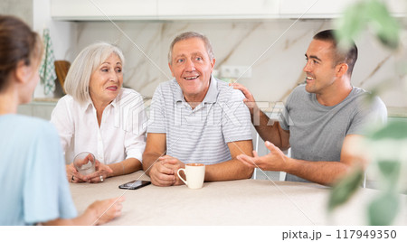 Family of four sits at table and talking Family of four sits at table and talking 117949350