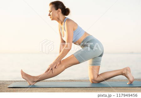 Young woman practicing different poses during yoga training on beach at sunset Young woman practicing different poses during yoga training on beach at sunset 117949456