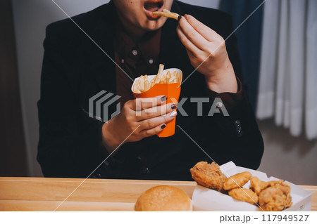 Asian woman holding french fries and eating happily in restaurant Asian woman holding french fries and eating happily in restaurant 117949527