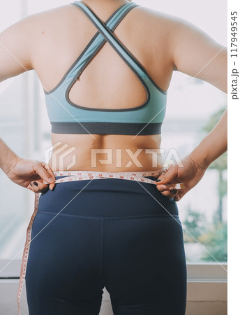 fat woman, fat belly, chubby, obese woman hand holding excessive belly fat with measure tape, woman diet lifestyle concept 117949545