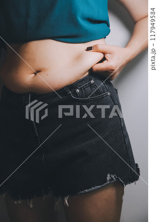 fat woman, fat belly, chubby, obese woman hand holding excessive belly fat with measure tape, woman diet lifestyle concept 117949584