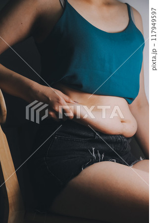 fat woman, fat belly, chubby, obese woman hand holding excessive belly fat with measure tape, woman diet lifestyle concept 117949597