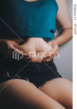 fat woman, fat belly, chubby, obese woman hand holding excessive belly fat with measure tape, woman diet lifestyle concept 117949602