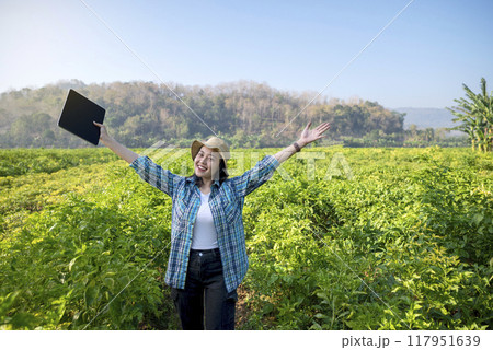 An Indonesian farmer girl is holding a tablet and smiling in a field of chili plants 117951639