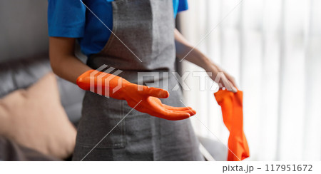 Housekeeper preparing for cleaning with orange gloves Housekeeper preparing for cleaning with orange gloves 117951672