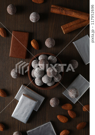 Chocolate balls in a wooden bowl with chocolate bars and almonds 117952696