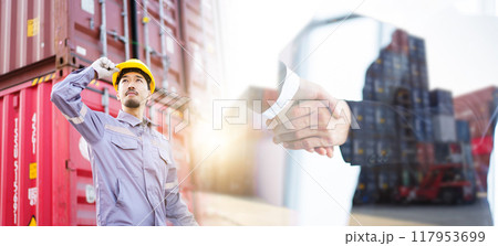 Portrait of smart and good looking Asian container yard or custom officer standing in the container yard and looking at the sky, photograph with double exposure showing businesspeople shaking hands. Portrait of smart and good looking Asian container yard or custom officer standing in the container yard and looking at the sky, photograph with double exposure showing businesspeople shaking hands. 117953699