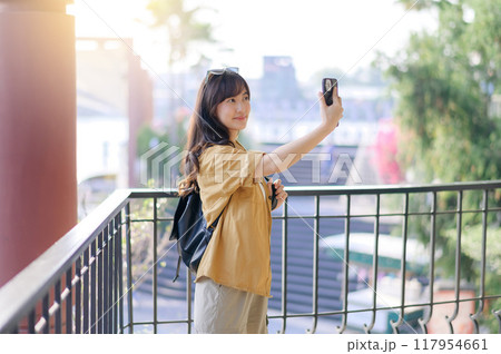 Traveler young asian woman in her 30s navigates Bangkok with her camera. Capture the world with confidence and share your unique story. 117954661