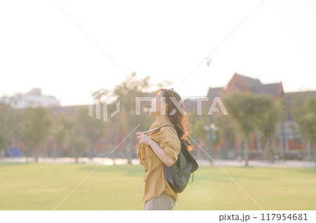 Traveler asian woman in her 30s stands bathed in the golden glow of sunset, embracing the freedom of exploration. on summer holiday weekend vacation trip in Bangkok, Thailand 117954681