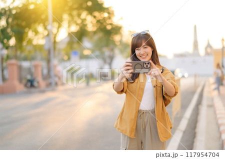 Traveler asian woman in her 30s using smartphone to take a photo while traveling urban street in Bangkok, Thailand Traveler asian woman in her 30s using smartphone to take a photo while traveling urban street in Bangkok, Thailand 117954704