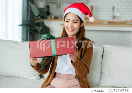 Young Asian woman wearing Christmas hat and opening a gift box 117954748