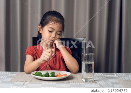 Little cute kid girl refusing to eat healthy vegetables. Children do not like to eat vegetables. Little cute kid girl refusing to eat healthy vegetables. Children do not like to eat vegetables. 117954775