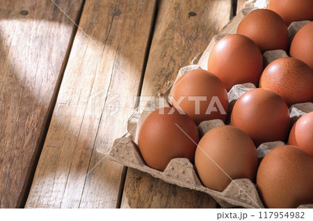 Fresh chicken eggs in cardboard boxes arranged on wooden background with copy space for text. Fresh chicken eggs in cardboard boxes arranged on wooden background with copy space for text. 117954982