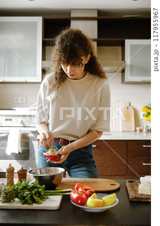 Woman stuffing bell peppers with grated cheese 117955967