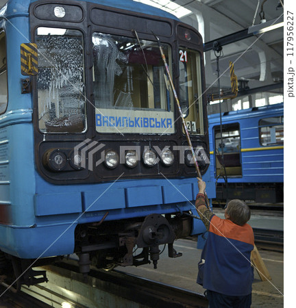 Old woman worker washing windows of a subway train parked on a pit of the depot 117956227