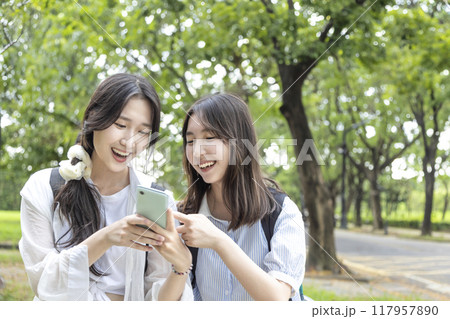 Happy teenage  girls having fun while using mobile phone in  school 117957890