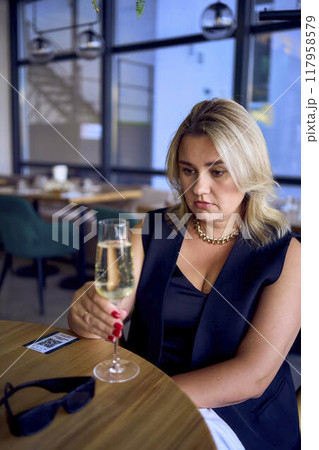 middle-aged plus size woman in old money style clothes drinking sparkling wine in a fancy restaurant middle-aged plus size woman in old money style clothes drinking sparkling wine in a fancy restaurant 117958579