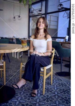 16-year-old teenage girl in old money style clothes drinks bumble coffee with an orange in a fancy restaurant 16-year-old teenage girl in old money style clothes drinks bumble coffee with an orange in a fancy restaurant 117958591