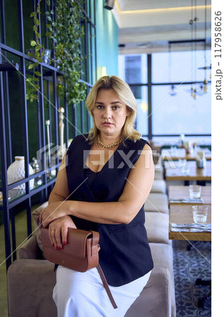 a  middle-aged plus size woman in old money style clothes in a fancy restaurant 117958626
