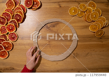 DIY process of woman making Christmas arrangement with dried oranges and grapefruits. Series of handmade craft instruction. Zero waste eco-friendly winter holiday decoration 117959440